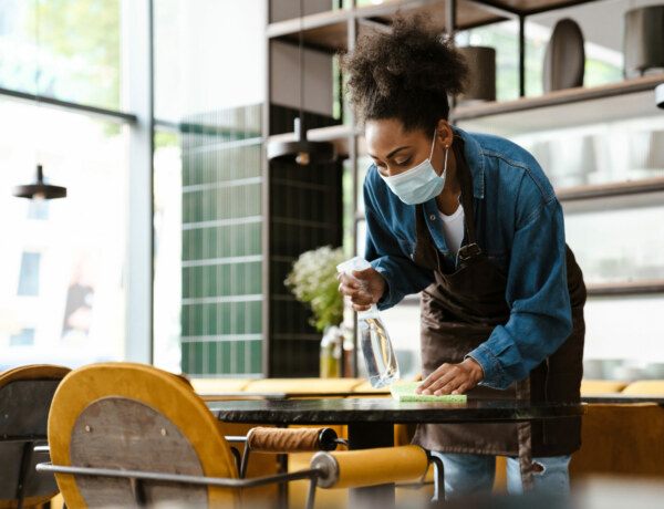 A person cleaning and disinfecting a table in a restaurant.